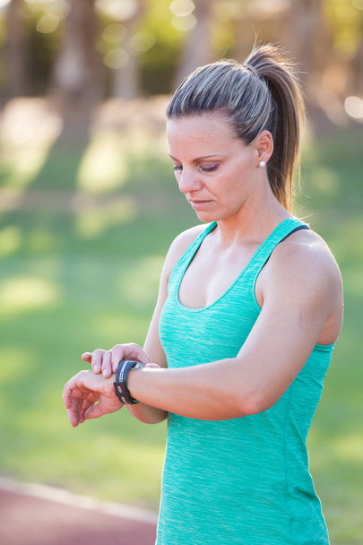 Fit female athlete looking at her watch - 写真・画像
