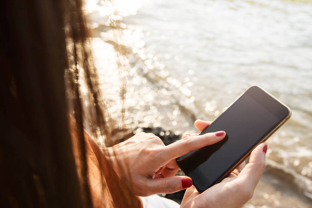 Mujer usando el teléfono inteligente en la playa de verano
 - Foto, imagen