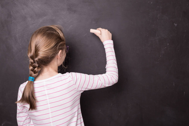 Blond chid girl (kid) writing on school chalkboard - Photo, image