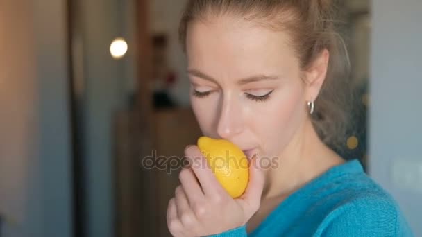 Jonge vrouw in een blauwe blouse inhaleert de geur van verse citroen. - Video
