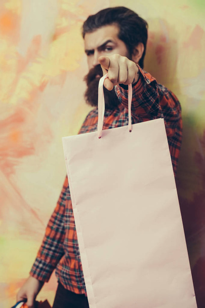 Homem barbudo sério apontando dedo com saco de compras
 - Foto, Imagem