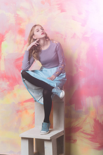 Pretty girl in blue skirt and sneakers on wooden chair - Foto, immagini