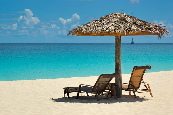 Zeer ontspannen rustige Caribbean weergave met een rieten dak paraplu en chaise lounge - Foto, afbeelding