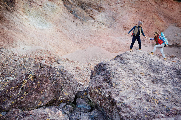 guy helping girlfriend climb rock - Valokuva, kuva