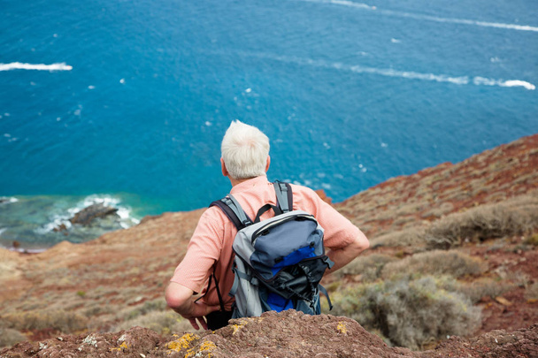 взрослый путешественник, стоящий на скале
 - Фото, изображение