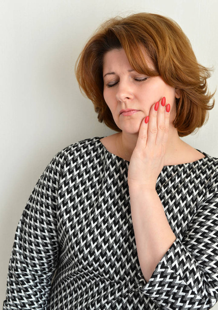 woman with toothache holds her cheek - Foto, afbeelding