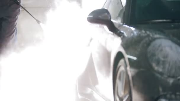 ガレージ自動車サービスの労働者は水ホースによって石鹸水で車を洗っています。 - 映像、動画