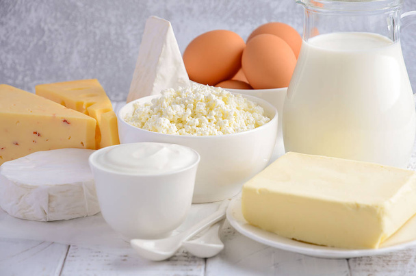 Świeże produkty mleczne. Mleko, ser brie, Camembert, masło, jogurt, ser i jaja na drewnianym stole. - Zdjęcie, obraz