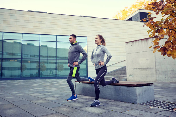 happy man and woman exercising on bench outdoors - Foto, Imagen