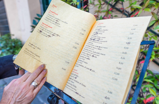Mulher mão tocando menu restaurante italiano
 - Foto, Imagem