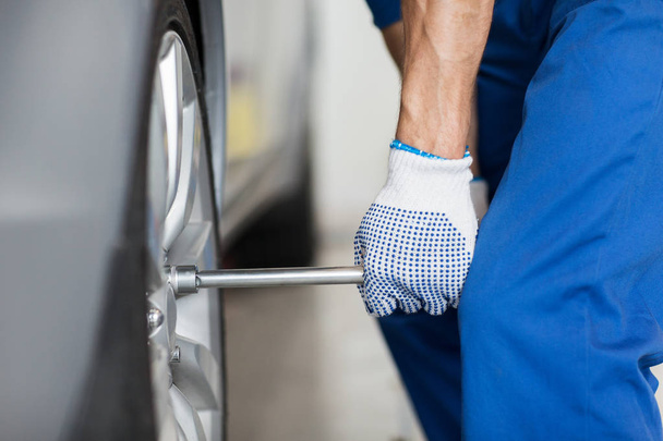 mechanic with screwdriver changing car tire - Photo, image