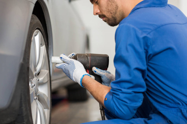 mechanic with screwdriver changing car tire - Foto, Imagen