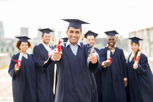 happy students with diplomas showing thumbs up - Фото, изображение