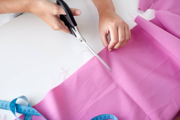 woman with tailor scissors cutting out fabric - Photo, image