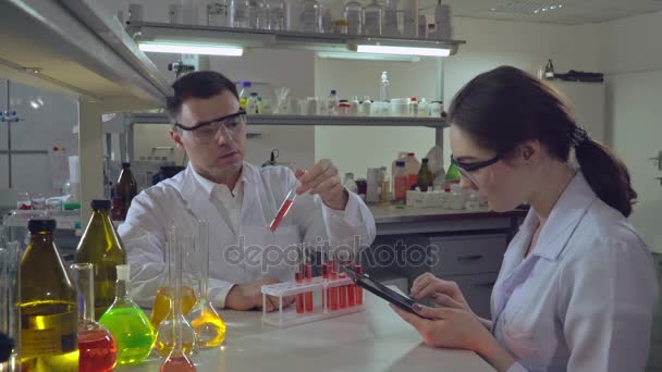 Ingénieur chimiste tenant le tube à essai avec le liquide parlant avec l'étudiant
. - Séquence, vidéo