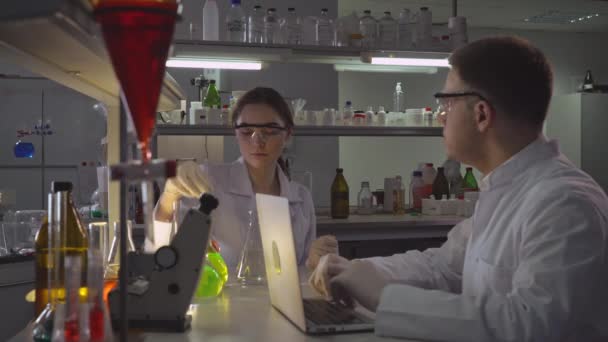Wetenschapper met assistent werken in laboratorium in de avond. - Video