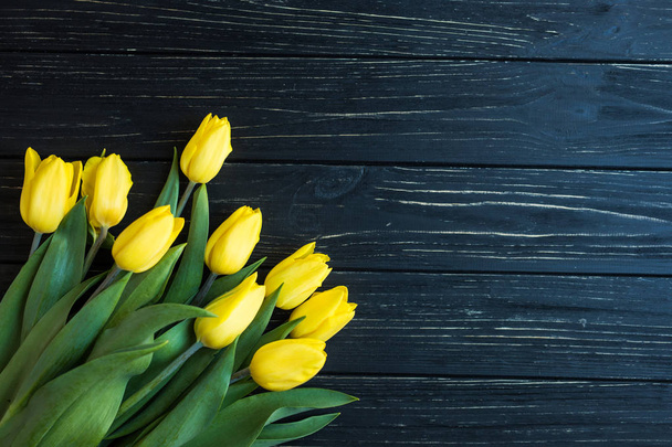 Bouquet of yellow tulips isolated on a black wooden background - Foto, Imagem