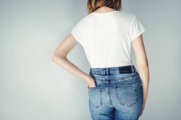 Mujer con jeans azules con cintura alta y camiseta blanca en blanco
 - Foto, Imagen