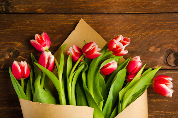 red white tulips on wooden boards. Bouquet of tulips in kraft paper - Fotoğraf, Görsel