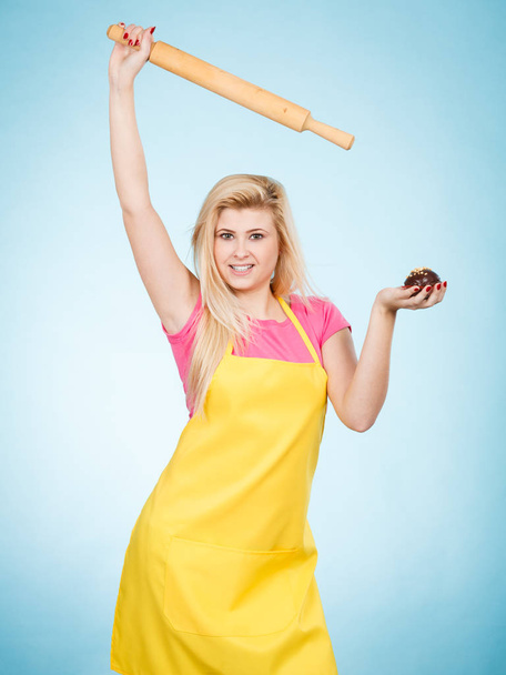 Woman holding cupcake and rolling pin wearing apron - Zdjęcie, obraz