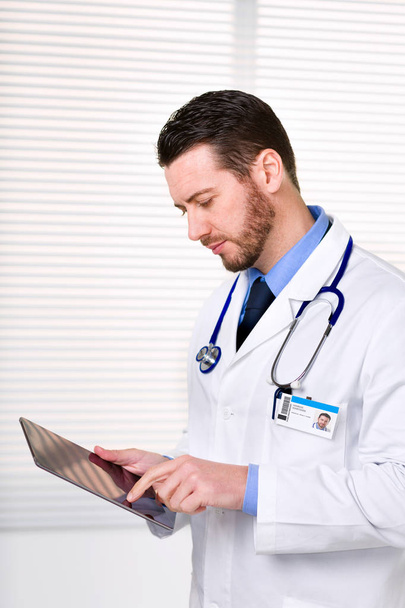 Αρσενικό ο γιατρός στέκεται ενώ εργάζεστε με tablet - Φωτογραφία, εικόνα