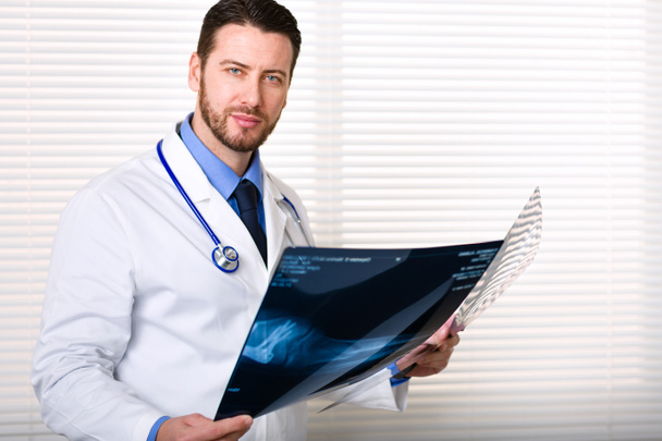Handsome male doctor portrait holding patients x-ray - Photo, Image