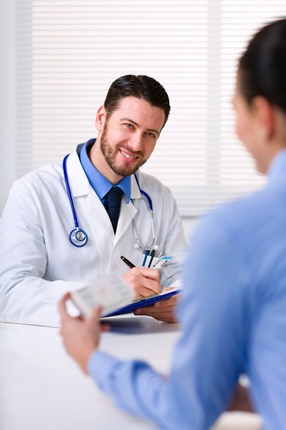 Doctor smiling while writing prescription - Photo, Image