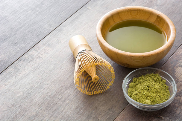 Matcha grüner Tee in einer Schüssel und Bambusbesen, auf Holzgrund - Foto, Bild
