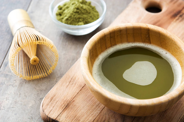 Маття зеленый чай в миске и бамбуковый венчик, на деревянном фоне
 - Фото, изображение