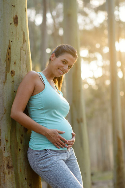 Pregnant sporty woman touching her belly - Foto, Imagen