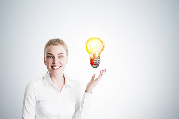 Happy blond woman and yellow light bulb - Photo, Image
