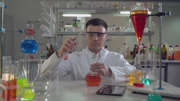 Przystojny naukowcem, trzymając kolbę w laboratorium - Materiał filmowy, wideo