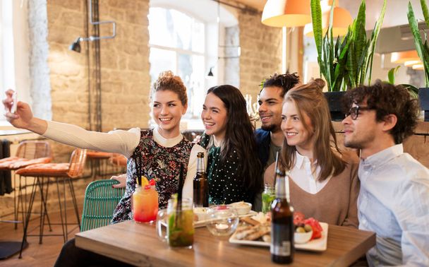 ystävät ottavat selfie älypuhelimella baarissa tai kahvilassa
 - Valokuva, kuva