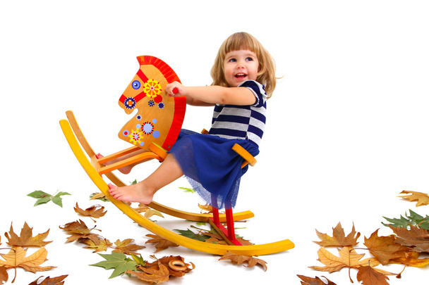A smiling little girl riding a wooden horse isolated on white ba - Фото, зображення