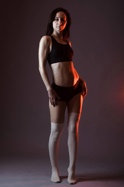 Athletic woman in top and shorts posing on gray background, full - Photo, Image
