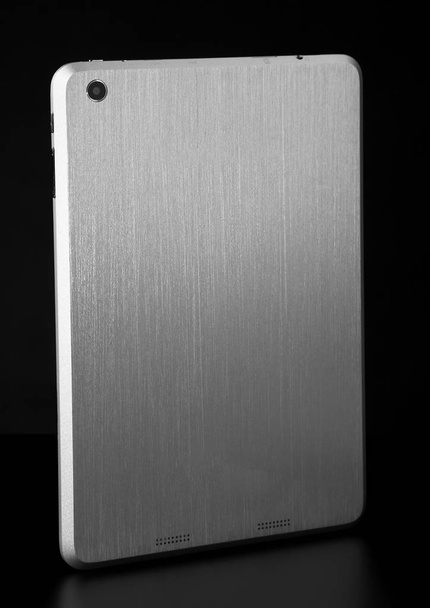 Tableta de metal blanco plateado sobre fondo negro sombra delgada espalda l
 - Foto, imagen