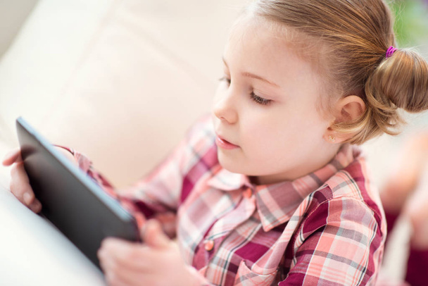 Pretty little child girl  using a digital tablet, looking and sm - 写真・画像