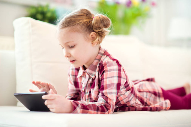 Pretty little child girl  using a digital tablet, looking and sm - Foto, Imagen