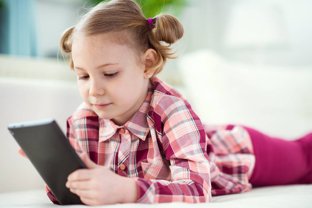 Pretty little child girl  using a digital tablet, looking and sm - Фото, зображення