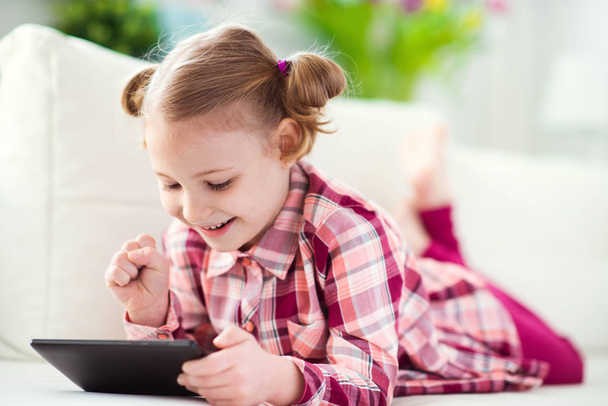 Pretty little child girl  using a digital tablet, looking and sm - Photo, Image