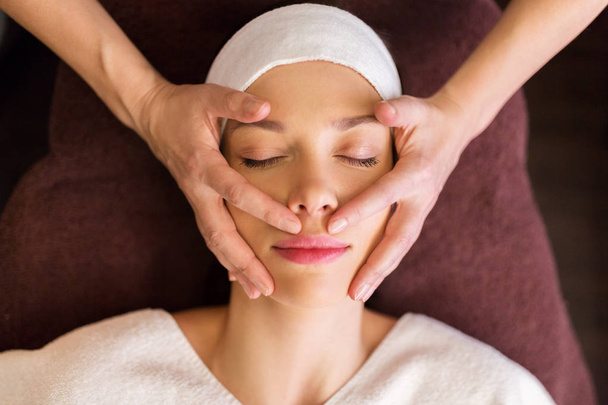 Frau mit Gesichts- und Kopfmassage im Wellnessbereich - Foto, Bild