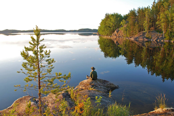 Hombre sentado en el lago Saimaa en Finlandia al atardecer
 - Foto, imagen