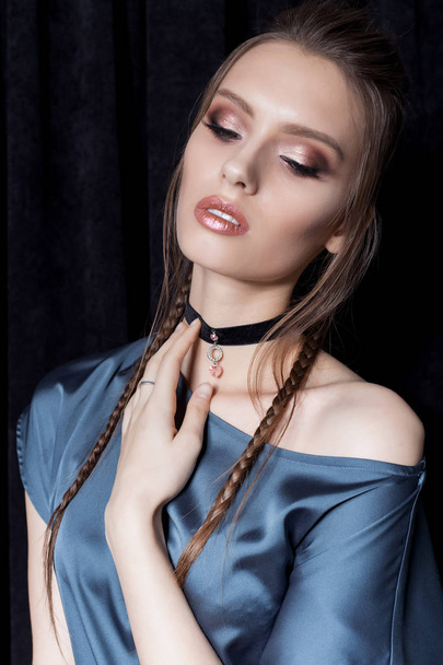 beautiful sexy young woman with dark hair braided with bright makeup and fashion jewelry choker around her neck, fashion jewelry shooting on a black background in the studio, hard light - Φωτογραφία, εικόνα