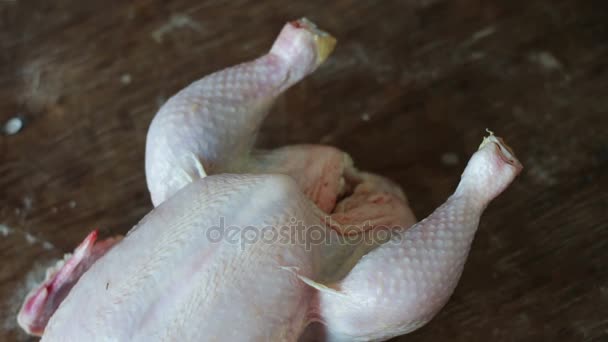 Χέρια προετοιμασία ολόκληρο ωμό κοτόπουλο σε ένα ξύλινο ταμπλό με μαγείρεμα - Πλάνα, βίντεο