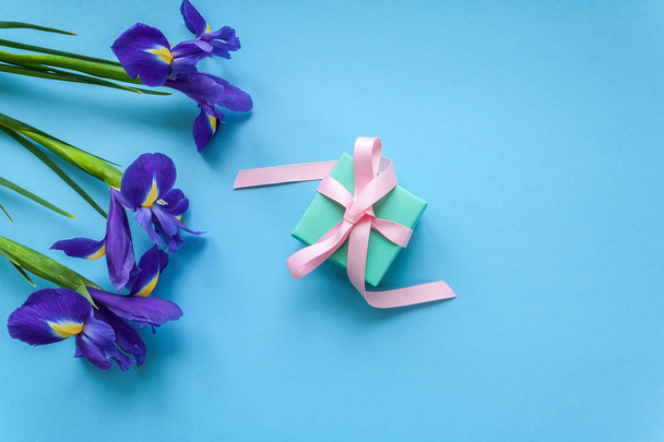 gift and three irises on blue background - Φωτογραφία, εικόνα