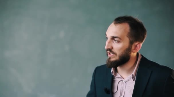 Barbudo hombre con chaqueta y camisa de rayas explica con confianza en la pared aislada
 - Metraje, vídeo