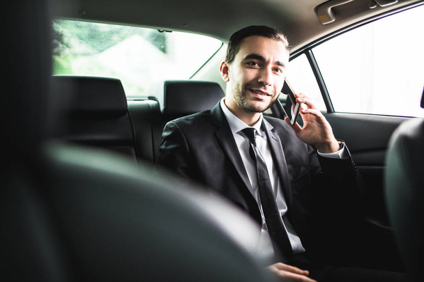 Businessman on call in car, smiling - Фото, зображення