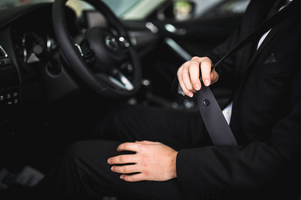 Close-up of man sitting in car fastening seat belt - Photo, image