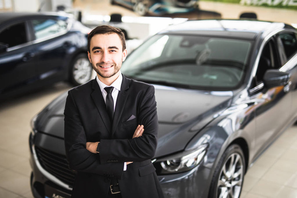 Handsome young classic car salesman standing at the dealership - Фото, изображение