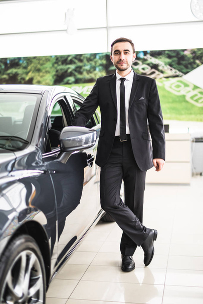 Handsome young classic car salesman standing at the dealership - Фото, изображение